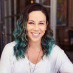 a woman with green hair smiling at the camera.