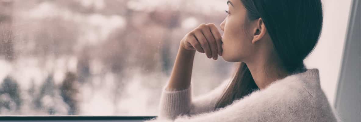 a woman looking out of a window with her hand on her chin.