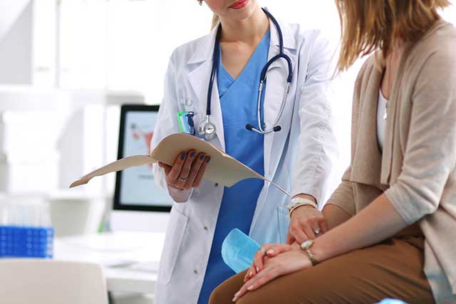 a woman in a doctor's coat talking to another woman.