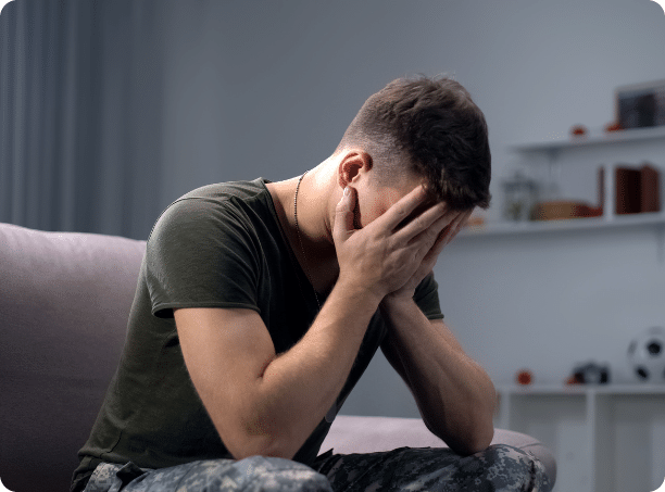 a man sitting on a couch holding his hands to his face.